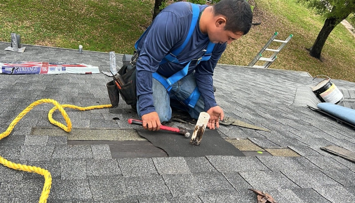 A roofing contractor wearing a branded hat points to a broken clay tile during a professional inspection to document damage for a roof insurance claim.