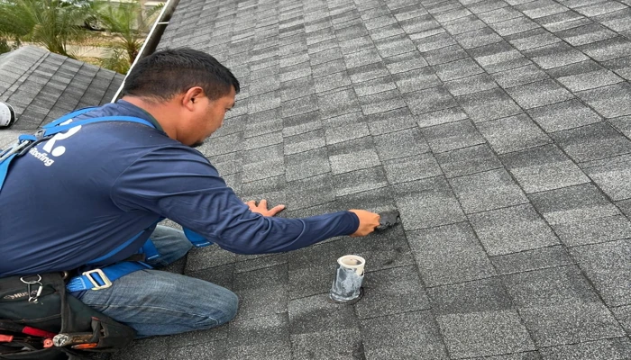 Technician inspecting and sealing asphalt shingles to show how to protect your roof during a hurricane with preventive maintenance.